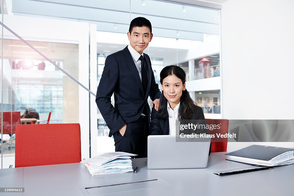 Asian businesspeople looking in camera with laptop