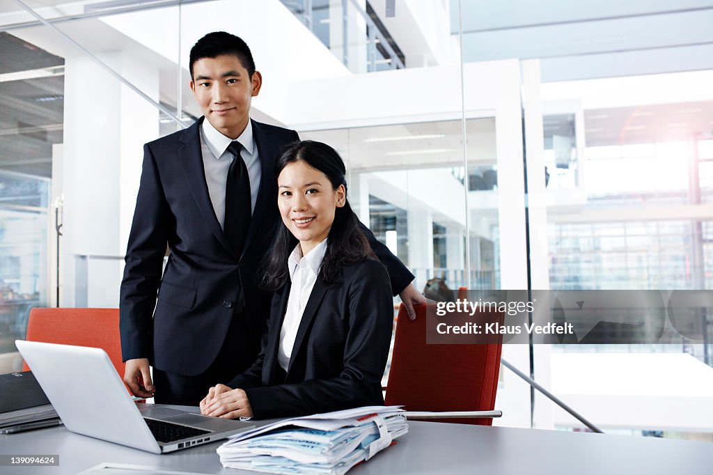 Asian businesspeople with laptop looking in camera