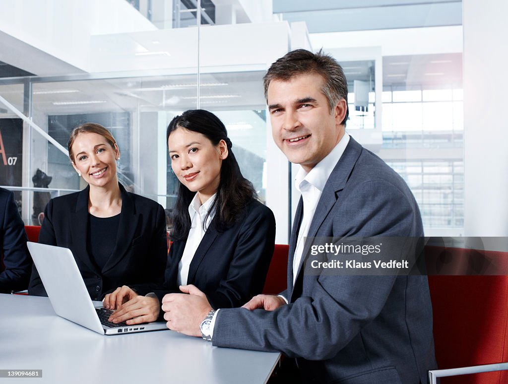 3 businesspeople sitting around laptop