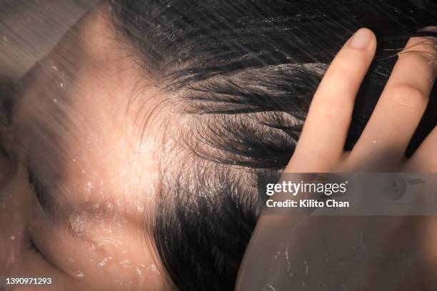 closeup of an asian woman taking a shower washing her hair - hand in hair foto e immagini stock
