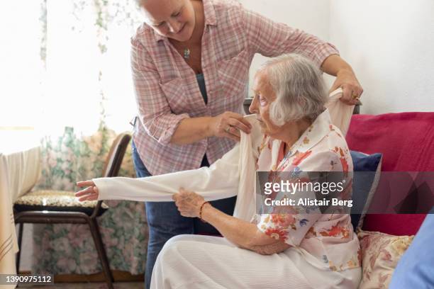 mature woman caring for her elderly mother - asistente sanitario fotografías e imágenes de stock