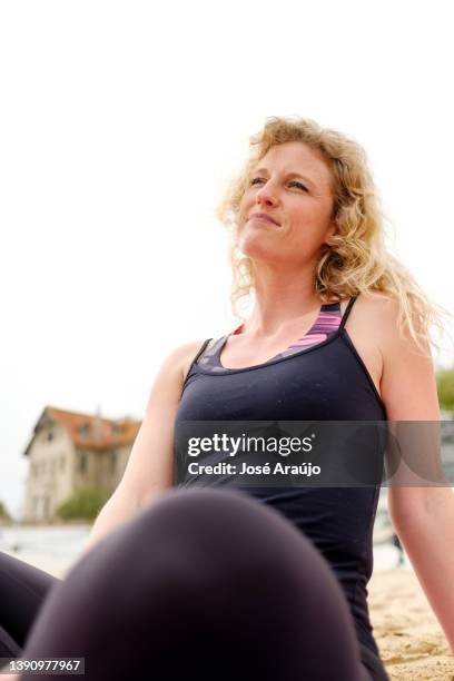 woman on the beach sitting on towel relaxing and looking at the sea - linha do horizonte sobre água stock pictures, royalty-free photos & images