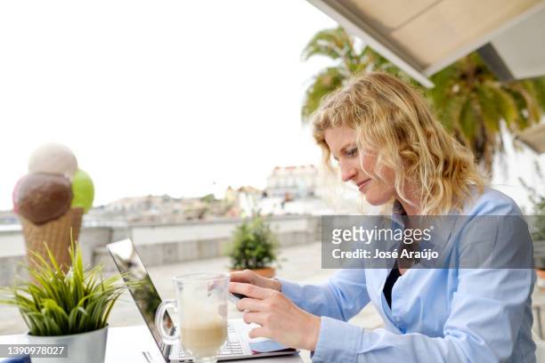 mujer trabajando desde una terraza de playa, en una reunión de zoom de teléfono inteligente - descontrair fotografías e imágenes de stock