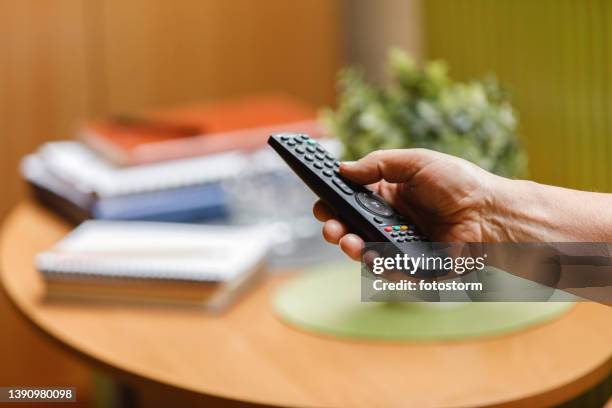 unrecognizable senior man changing a channel on tv with a remote - remote control stock pictures, royalty-free photos & images