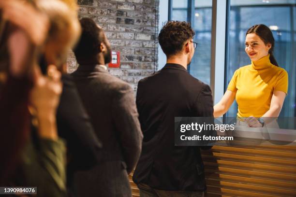 young female receptionist standing behind front desk, talking to a businessman - customers lining up stock pictures, royalty-free photos & images