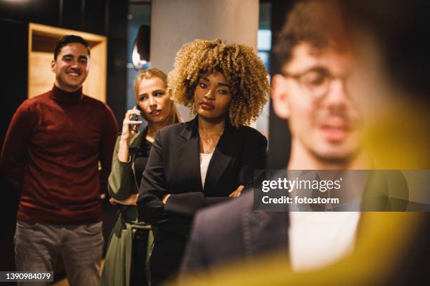 annoyed people waiting in line to be hosted by a receptionist at front desk - line up stockfoto's en -beelden