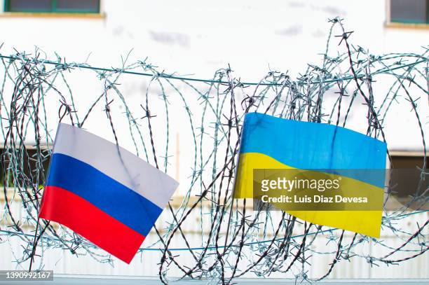 russian and ukrainian flag on barbed wire - konflikt stock-fotos und bilder