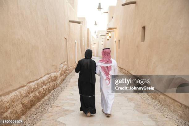 rückansicht des nahöstlichen paares, das das freilichtmuseum besucht - arab woman walking stock-fotos und bilder