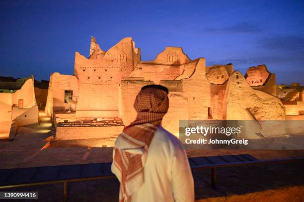 saudi man admiring illuminated salwa palace at twilight - suadi arabia stockfoto's en -beelden