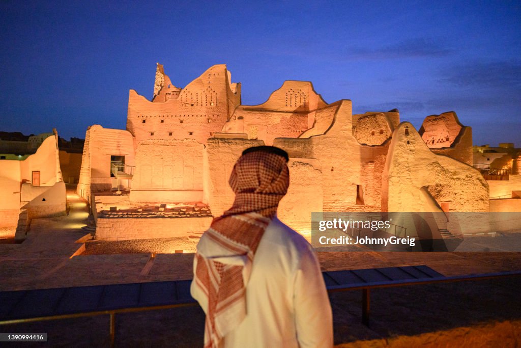 Saudi man admiring illuminated Salwa Palace at twilight