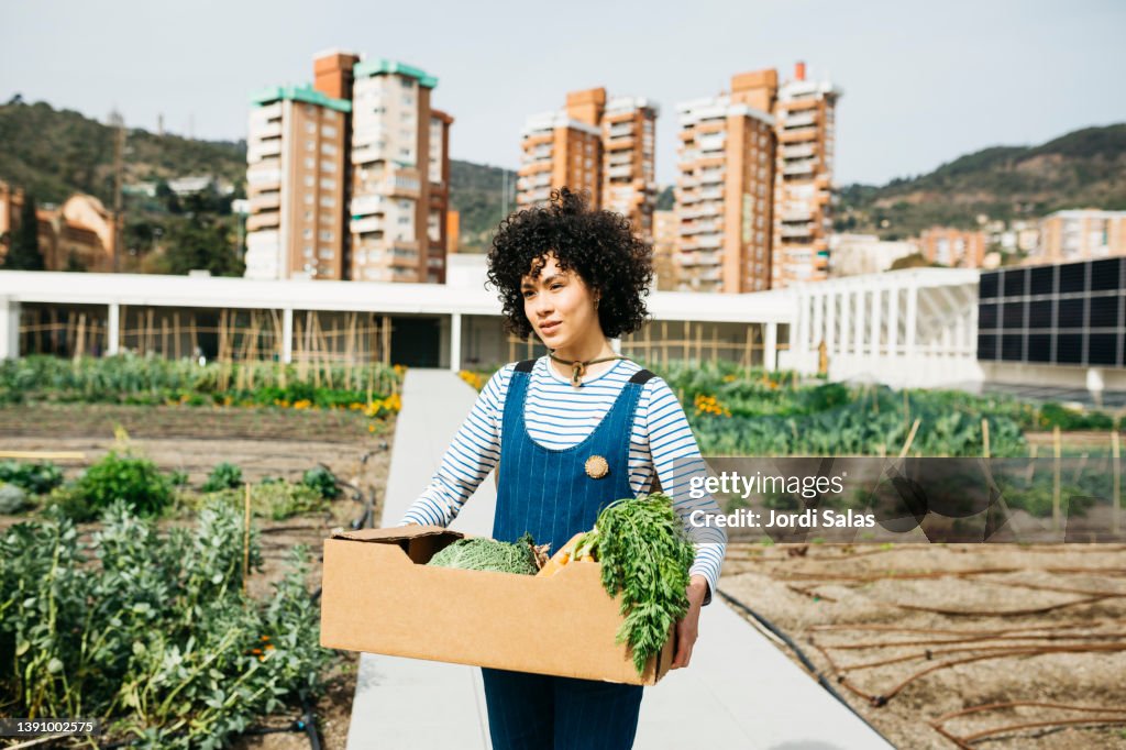 Woman carrying a box with vegetables