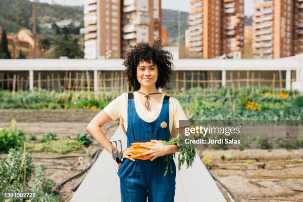 woman holding a bunch of carrots in a garden - the roof gardens stock pictures, royalty-free photos & images