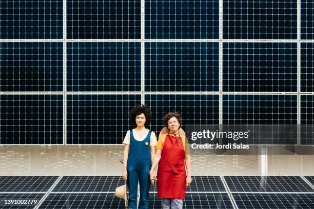 two women standing in front of a solar panel installation, - green economy stockfoto's en -beelden