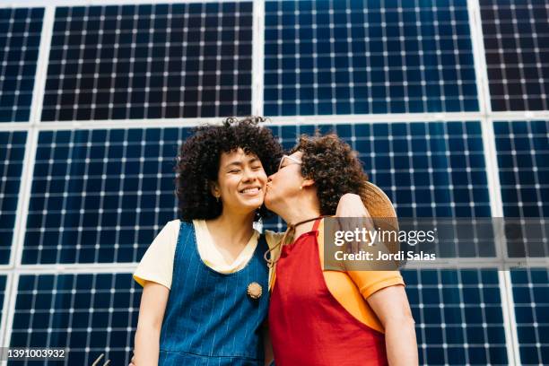 two women standing in front of a solar panel installation, - community garden family stock pictures, royalty-free photos & images