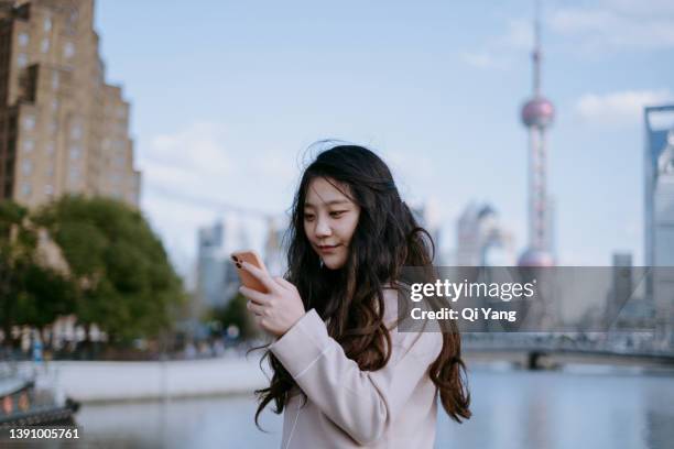 confident asian woman using smartphone in financial district, shanghai, china - shanghai calling stock pictures, royalty-free photos & images