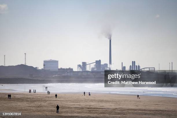 People walk on Aberavon beach near Port Talbot steelworks on April 9, 2022 in Port Talbot, Wales.