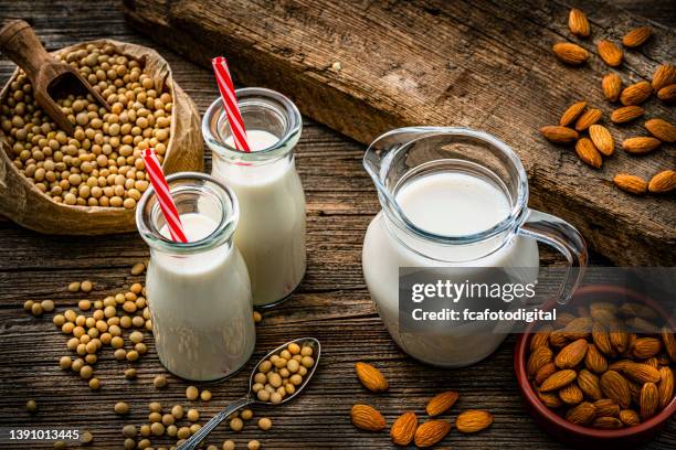 sojamilch und mandelmilch auf rustikalem holztisch - almond milk stock-fotos und bilder