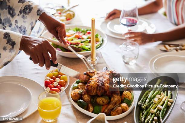 grandmother carving up a delicious roast chicken for a family dinner - roast chicken stock pictures, royalty-free photos & images