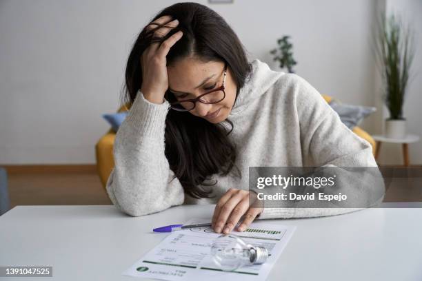 woman looking worried while checking electricity bill at home. - high imagens e fotografias de stock