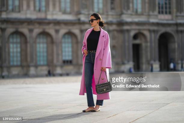 Sylvia Haghjoo wears a black satin headband, black sunglasses from Celine, navy blue stone and gold borders large earrings, a black t-shirt, a pink...