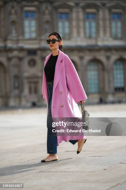 Sylvia Haghjoo wears a black satin headband, black sunglasses from Celine, navy blue stone and gold borders large earrings, a black t-shirt, a pink...