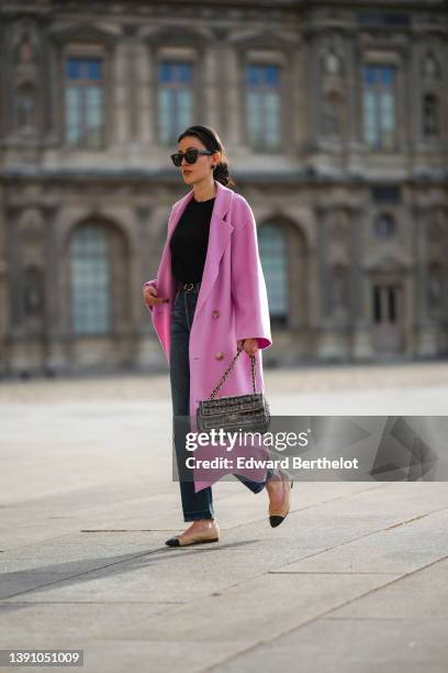 Sylvia Haghjoo wears a black satin headband, black sunglasses from Celine, navy blue stone and gold borders large earrings, a black t-shirt, a pink...