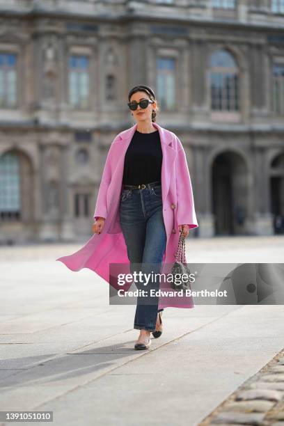 Sylvia Haghjoo wears a black satin headband, black sunglasses from Celine, navy blue stone and gold borders large earrings, a black t-shirt, a pink...