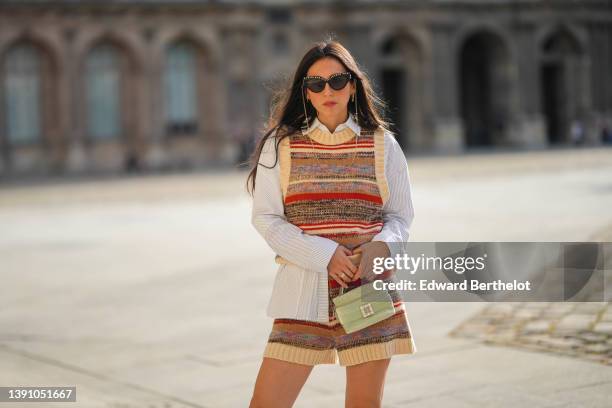 Gabriella Berdugo wears black with embroidered white pearls details and gold chain sunglasses, a white striped print pattern shirt, a brown / pale...