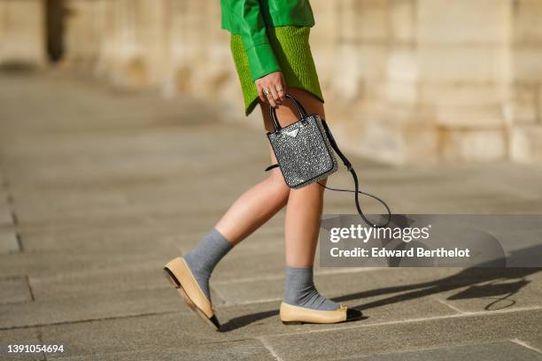 Gabriella Berdugo wears a green shiny leather buttoned jacket, a green embossed pattern satin short skirt, gold rings, a black shiny leather withe...
