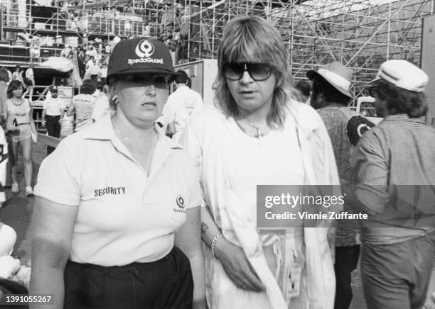 Member of security with British singer and songwriter Ozzy Osbourne, who was reuniting with his former band Black Sabbath, backstage at the Live Aid...