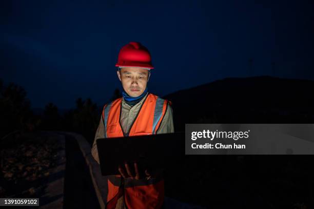 at night, an asian male engineer works with a computer in a wind power station - energy efficient building stock pictures, royalty-free photos & images