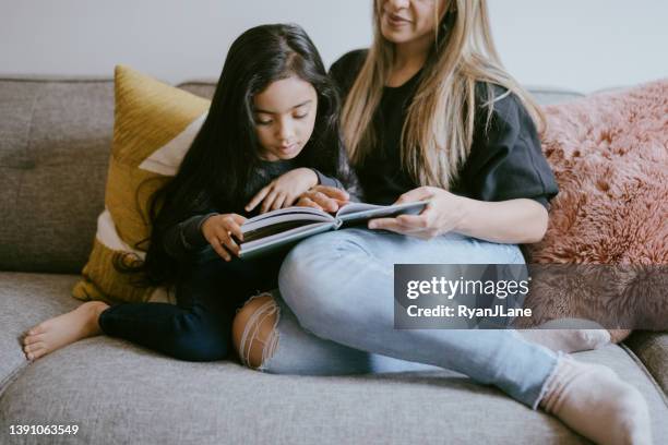 mother reading her young daughter a book - indian family in their 40's with kids imagens e fotografias de stock