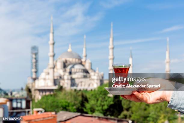 man drinking turkish tea with view of blue mosque in the background, istanbul, turkey - istanbul stockfoto's en -beelden