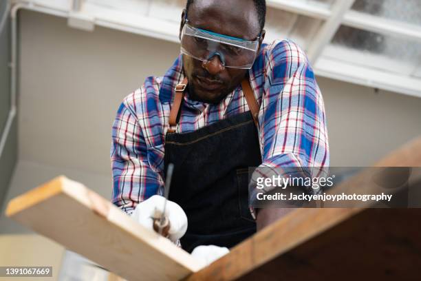 man cutting through block of wood using saw - wood worker posing ストックフォトと画像