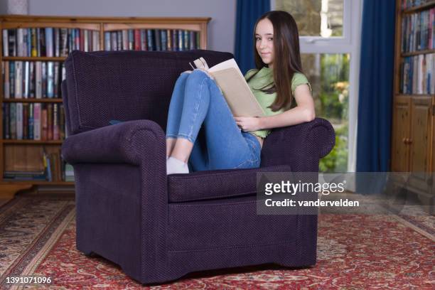 teen girl reading in her study - curled up reading book stock pictures, royalty-free photos & images