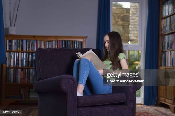 teen girl reading in her study - curled up reading book stock pictures, royalty-free photos & images