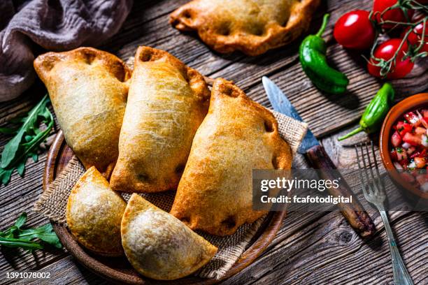 tabla de empanadas argentinas picantes sobre mesa de madera - empanadilla fotografías e imágenes de stock
