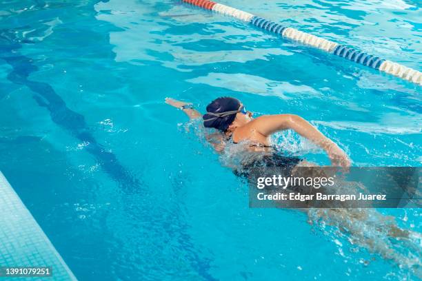 young latin woman swimming her arms while swimming in an olympic pool. woman practicing swimming - woman swimmer freestyle stock pictures, royalty-free photos & images