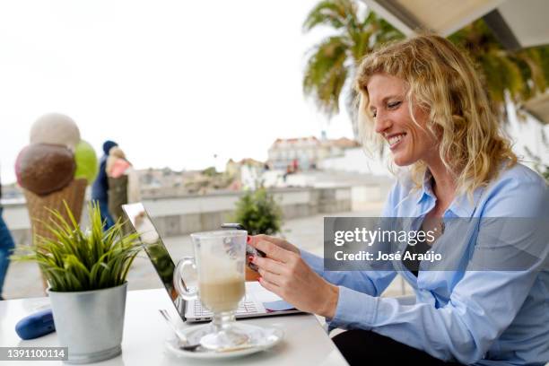 woman working from a beach terrace, in a smartphone zoom meeting, - pessoas notebook stock pictures, royalty-free photos & images