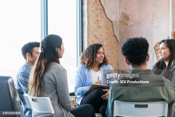 therapy group listens attentively as young woman shares - grupo pequeno de pessoas imagens e fotografias de stock