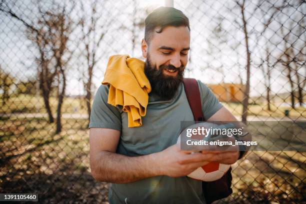 happy sportsman writing a message on his phone - football phone stock pictures, royalty-free photos & images