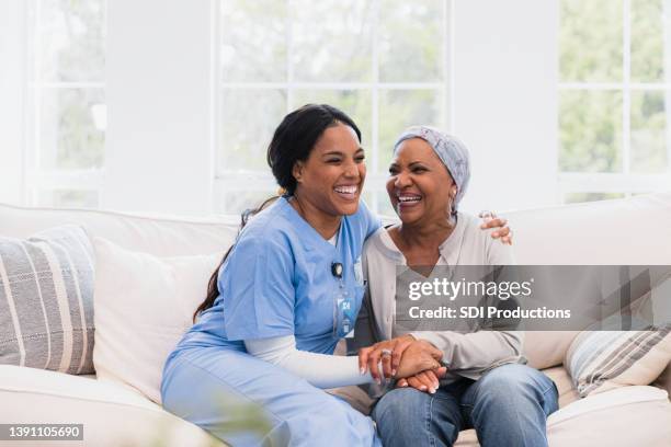 la enfermera de salud en el hogar y la paciente femenina se abrazan y ríen juntas - healthcare worker fotografías e imágenes de stock