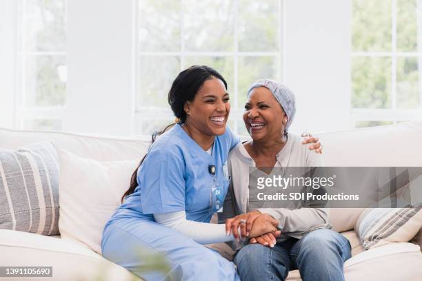 home health nurse and female patient embrace and laugh together - hospice 個照片及圖片檔