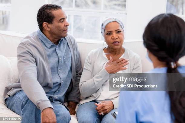 senior woman holds her chest while talking to the nurse - hospice bildbanksfoton och bilder