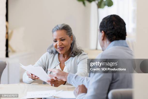 senior woman smiles as unrecognizable male insurance agent explains paperwork - old document stock pictures, royalty-free photos & images