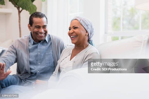 senior couple smiles and laughs at joke - woman couple at home stockfoto's en -beelden