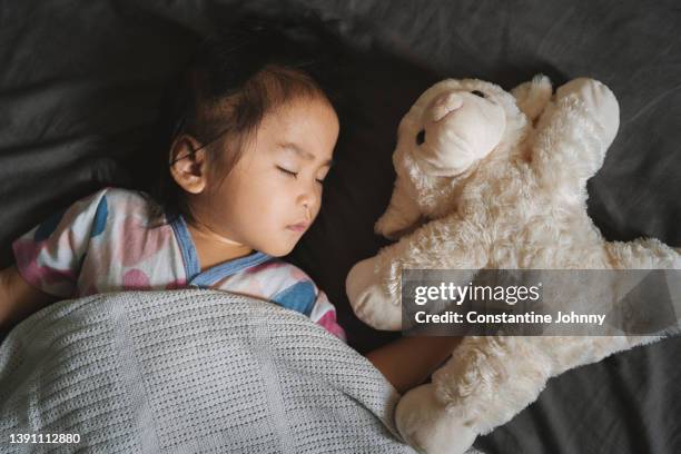 toddler girl sleeping on bed with her stuffed toy - sleeping toddler bed stock pictures, royalty-free photos & images