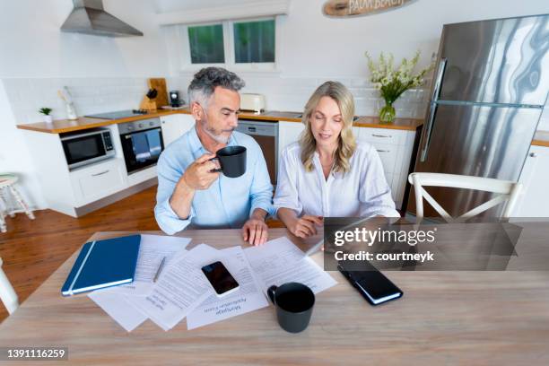 mature couple doing paperwork and paying bills at home. - sadness concept stock pictures, royalty-free photos & images