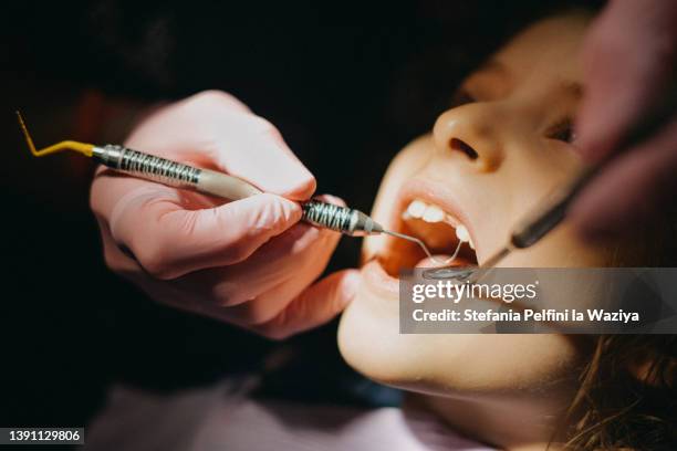 little girl having her teeth checked during a dentist visit - kinderzahnheilkunde stock-fotos und bilder