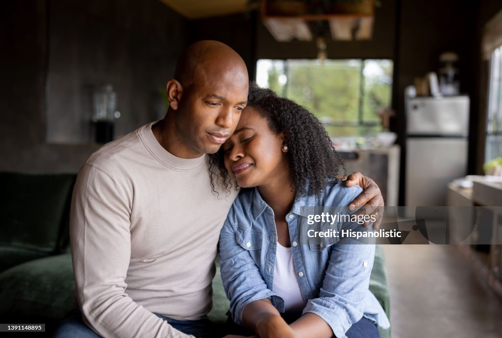 Loving husband consoling his sad wife crying at home